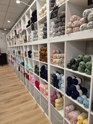 Regal mit bunten Wollknäueln in verschiedenen Farben und Texturen.